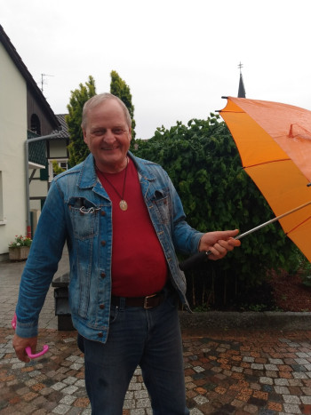 Autor Andrzej Żubrycki, uśmiechnięty starszy pan, trzymający parasolkę